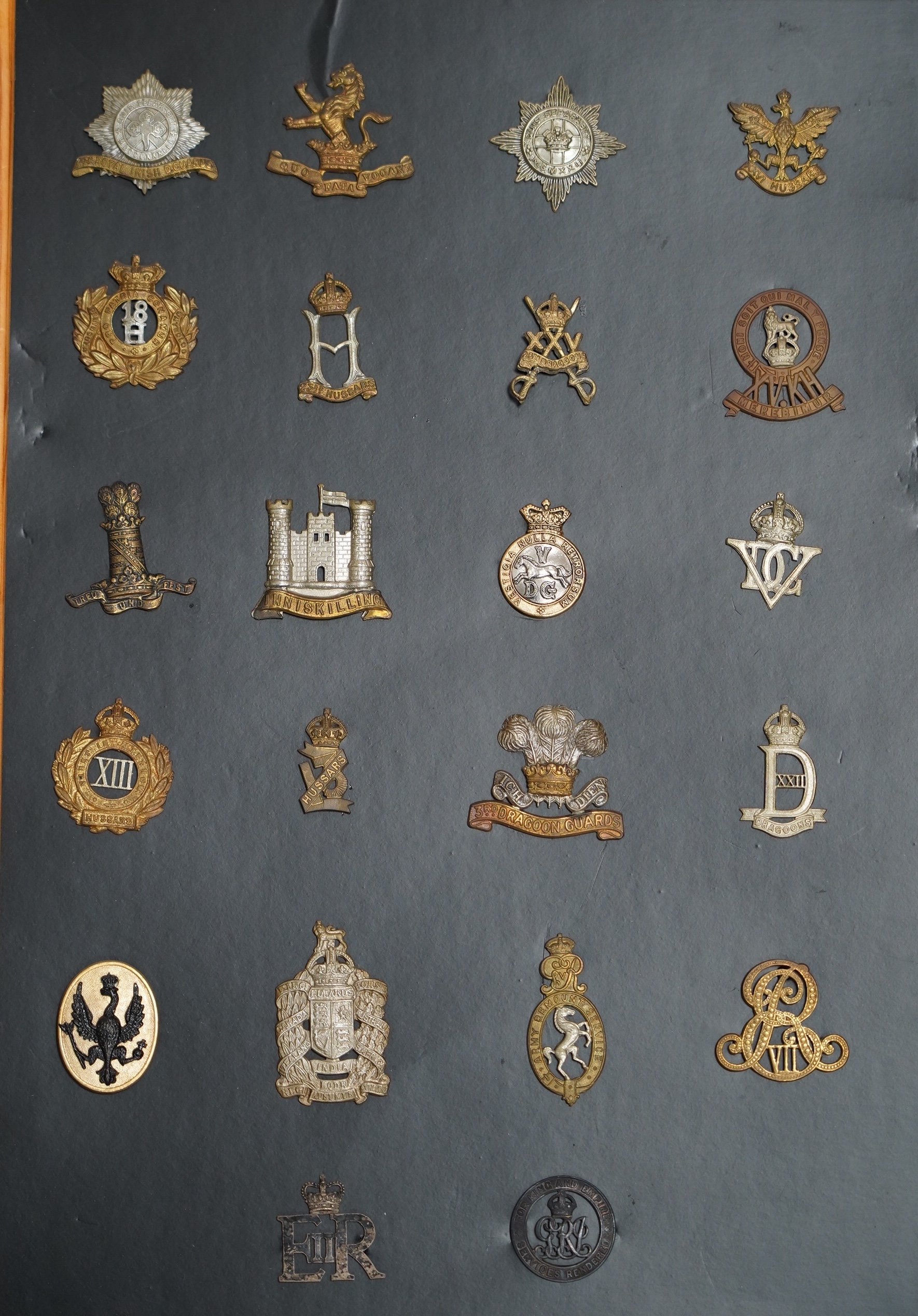 A collection of fifty-eight military cap badges, plus a few shoulder titles, mounted on four boards including; 26th Hussars, Inniskilling Regiment, 3rd Dragoon Guards, the Cheshire Regiment, Loyal North Lancashire, the N